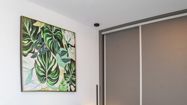 A modern bedroom with a bed, pillows, a nightstand, a wall-mounted light, and a large abstract painting. - Thyme Aroma - Quiet Nature Patio (Rethymno)