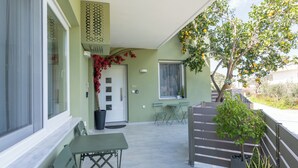 A covered outdoor area with a table and chairs, a potted plant, and a decorative wall panel. - Thyme Aroma - Quiet Nature Patio (Rethymno)