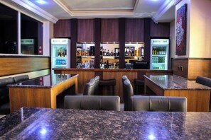 Zona de bar con asientos, una barra y un refrigerador con la etiqueta 'RESTP INT'.