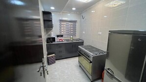 A compact kitchen with a gas stove, oven, and a refrigerator. - TOUX HOMES (Abuja)