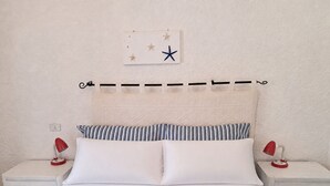 A bed with white and blue bedding, two striped pillows, and a starfish decoration on the wall. - Family Oasis: Pool and Garden - Baja Sardinia (Arzachena)