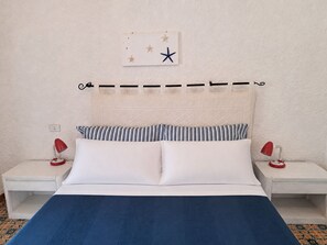Ein Bett mit weißer und blauer Bettwäsche, zwei gestreifte Kissen und eine Meerstern-Dekoration an der Wand.
