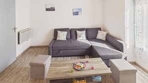 A modern living room with a grey sectional sofa, a wooden coffee table, and a radiator on the wall. - House for 4 adults 2 kids, walk everywhere (Ile Tudy)