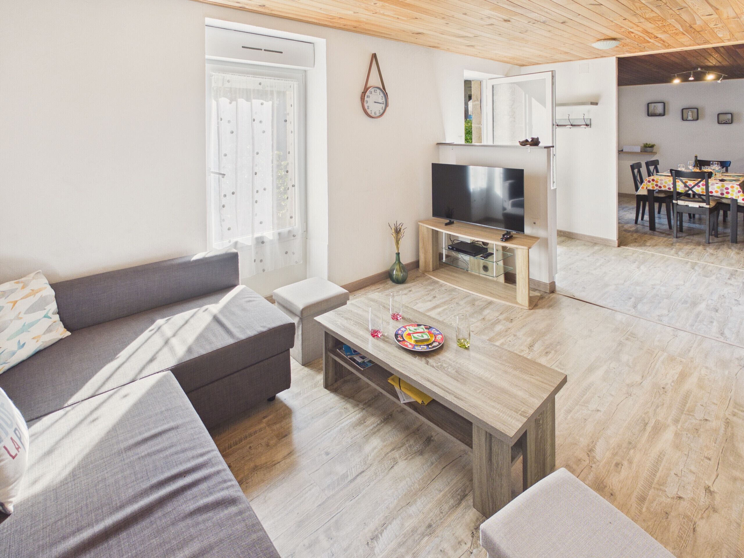 A living room with a sofa, coffee table, TV, and a dining area with chairs and a table.