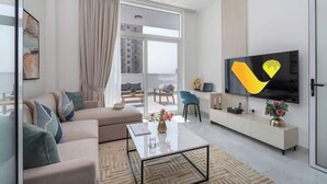 Una sala de estar moderna con sofá, mesa de centro, televisor y vistas a la ciudad.