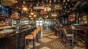 Un bar con suelo de cuadros, lámparas colgantes y varios letreros.