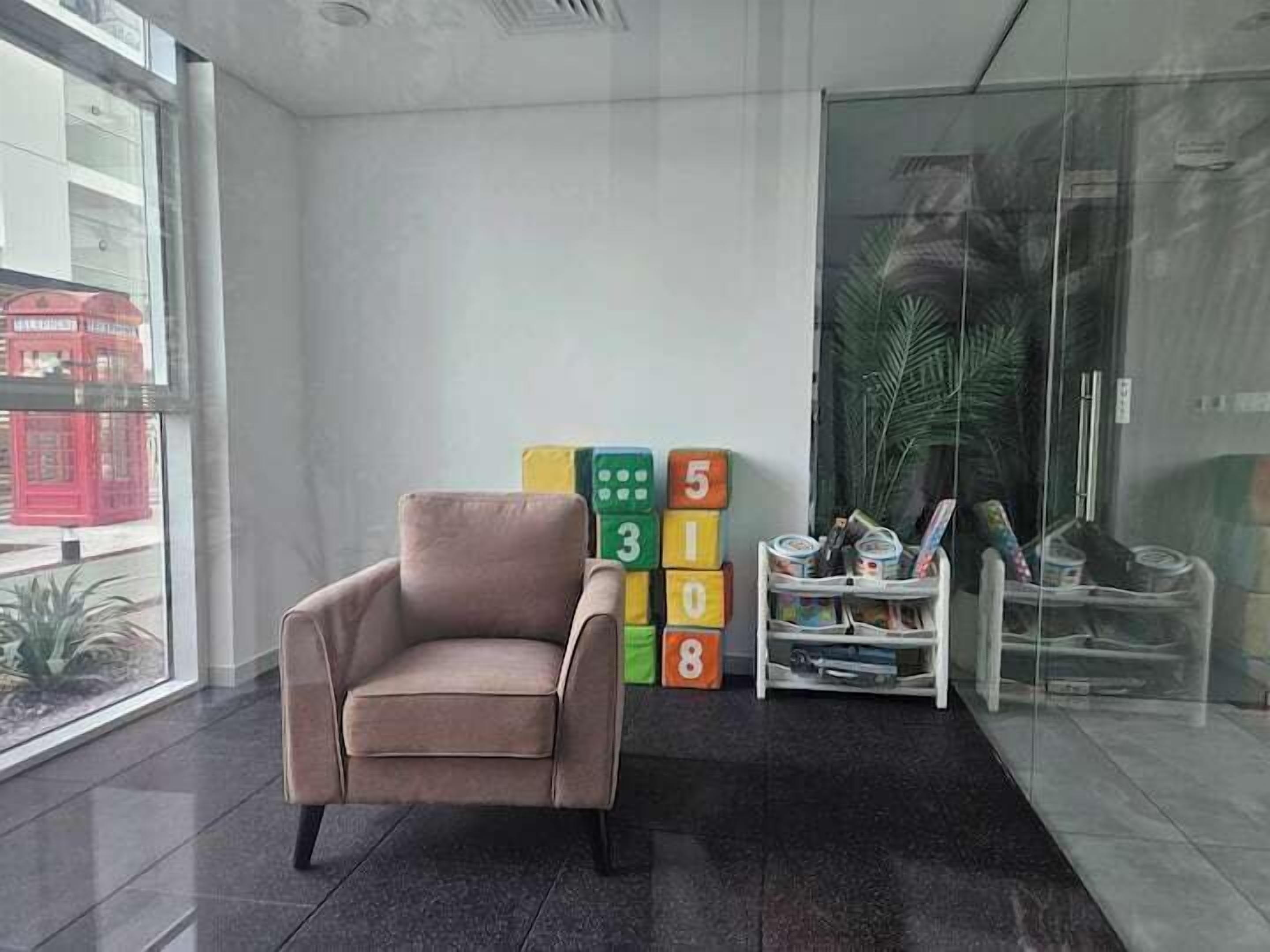 A modern office space with a beige chair, a glass partition, and a stack of colorful blocks.