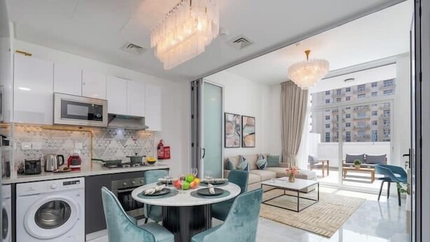 Una cocina moderna con microondas, lavadora y comedor con sillas y una mesa.