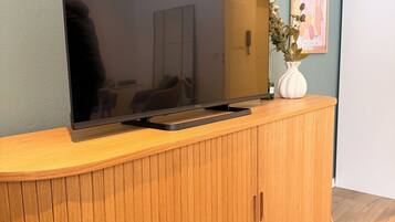 A flat-screen TV mounted on a wooden cabinet with a vase of flowers on top.