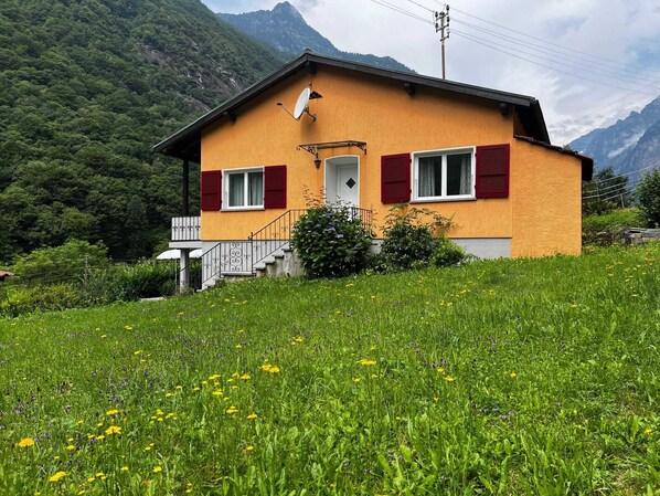 A house with a red door, white shutters, and a satellite dish.