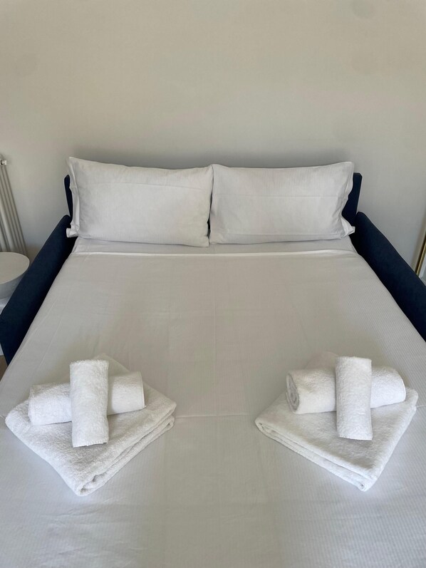 A hotel room with a large bed, two pillows, and two towels placed on the bed. - Vaticano Venticinque Guest House (Rome)