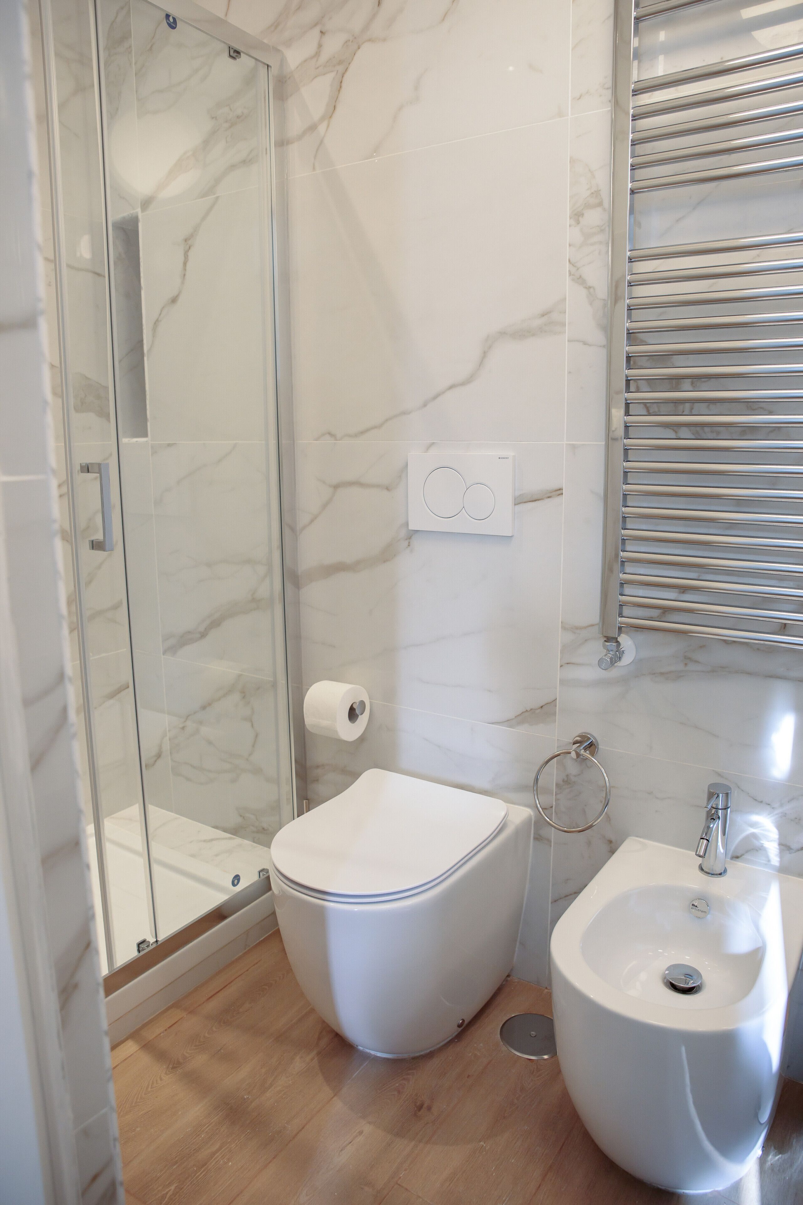 A bathroom with a glass shower enclosure, a toilet, and a sink.