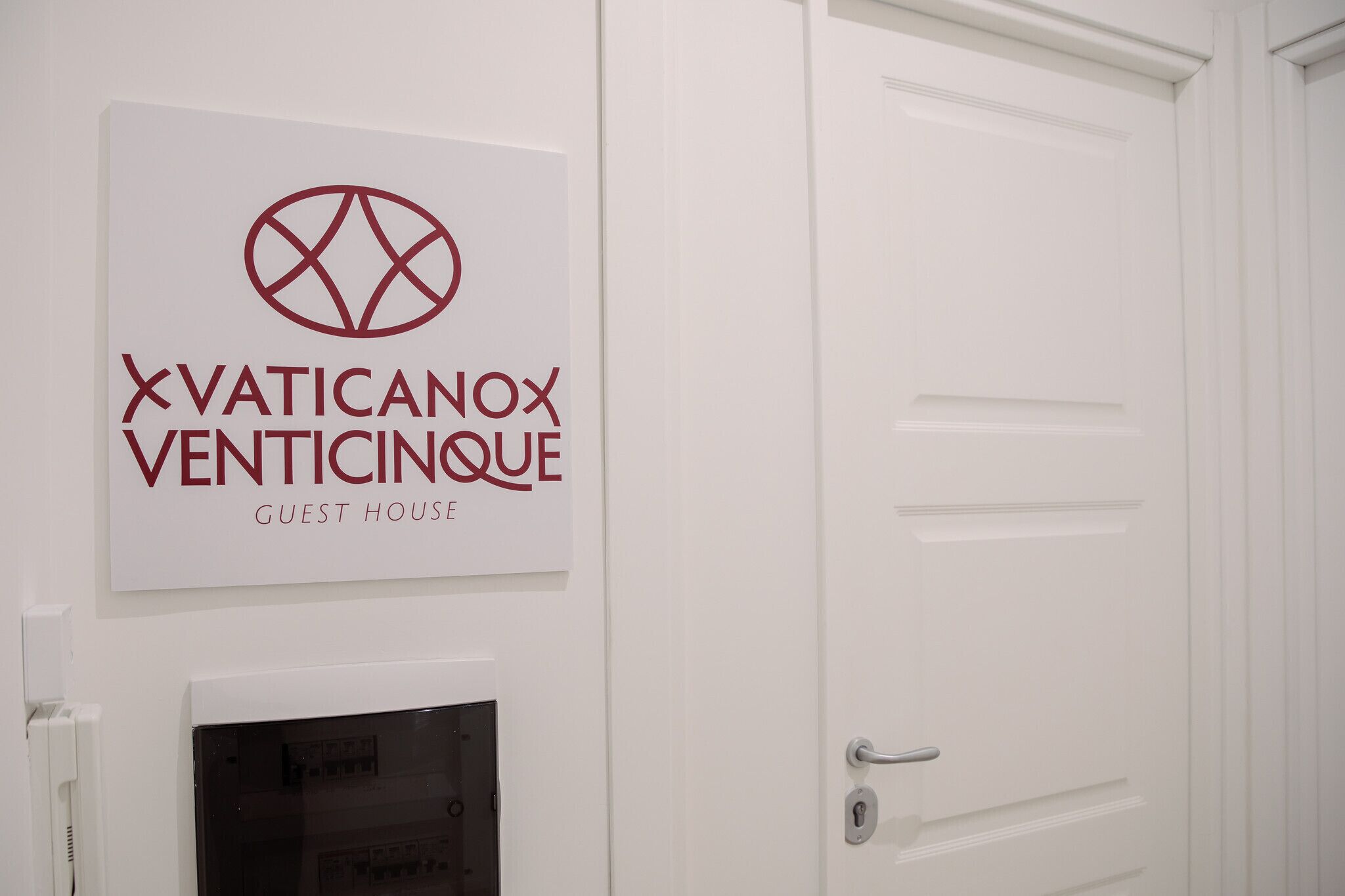 Μια πινακίδα με την ένδειξη «Vaticanox Venticinoe Guest House», με μια πόρτα και ένα παράθυρο.