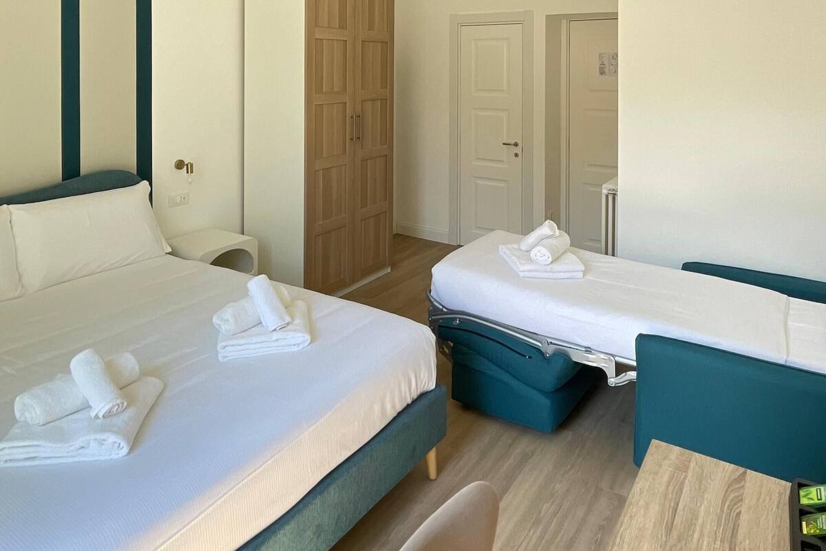 Ein Hotelzimmer mit zwei Betten, einem Holzschrank, einer Tür und einer Deckenleuchte.