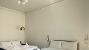 Une chambre d’hôtel avec deux lits, une table de chevet, une lampe et un luminaire au plafond.