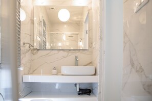 Une salle de bain moderne avec un lavabo en marbre, un miroir et une douche.