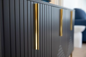 Un meuble moderne de couleur sombre, aux lignes verticales et aux poignées dorées.