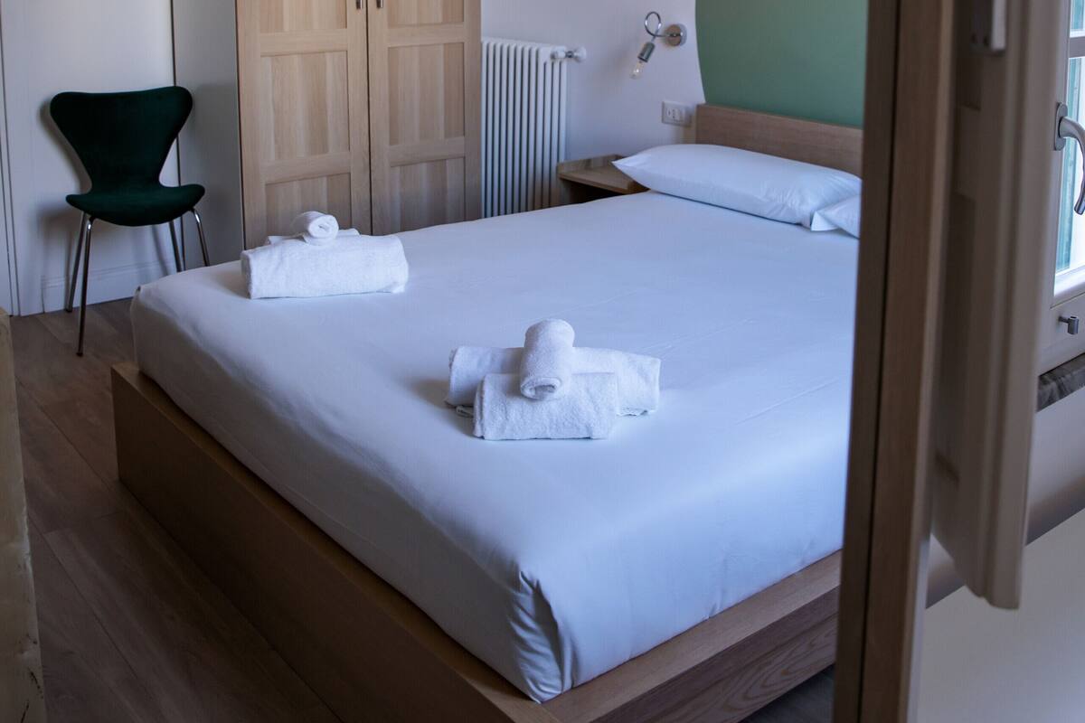 Ein Hotelzimmer mit Bett, Holzschrank, Heizkörper und grüner Wand.