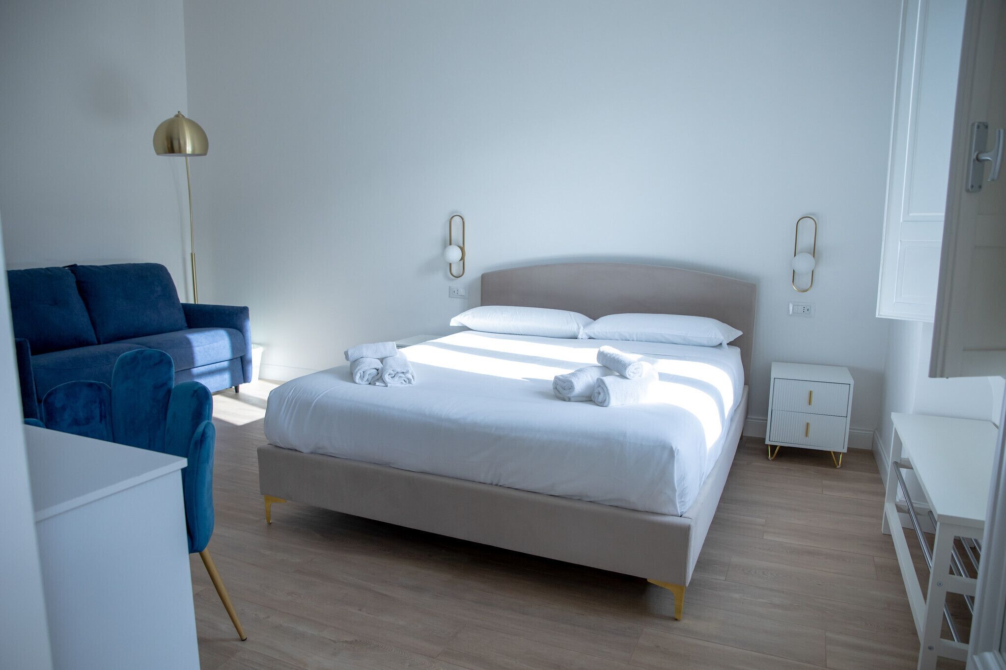 Ein Schlafzimmer mit einem Bett, Nachttischen, einer Lampe, einem Sessel und einem Schreibtisch.