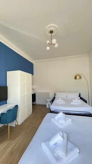 Een hotelkamer met een bed, een bureau, een kledingkast, een radiator en een plafondlamp.