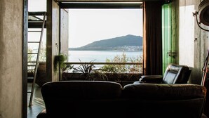 A room with a view of a lake and a mountain, a green door, and a leather chair. - Luxury Waterfront Loft with Panoramic Views (Caminha)