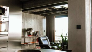 A modern kitchen with a large island, a microwave, and a seating area with a chair and plants. - Luxury Waterfront Loft with Panoramic Views (Caminha)
