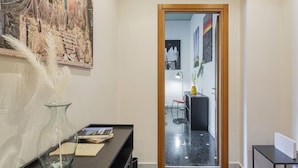 A hallway with a mirror, a vase with feathers, a desk with books, and a door leading to another room. - Albaro Sun House by Wonderful Italy (Genova)