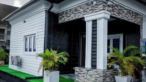 A white building with a black door, columns, and potted plants. - Livin Lagos Shortstays (Lekki)