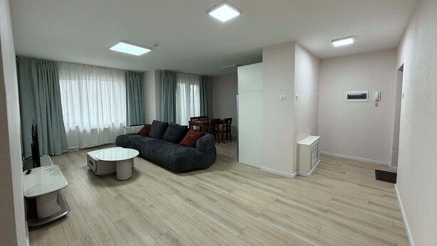 A modern living room with a sofa, a coffee table, and a dining area with chairs. - 44 Prime Location 1BR | New Furniture (Ulaanbaatar)