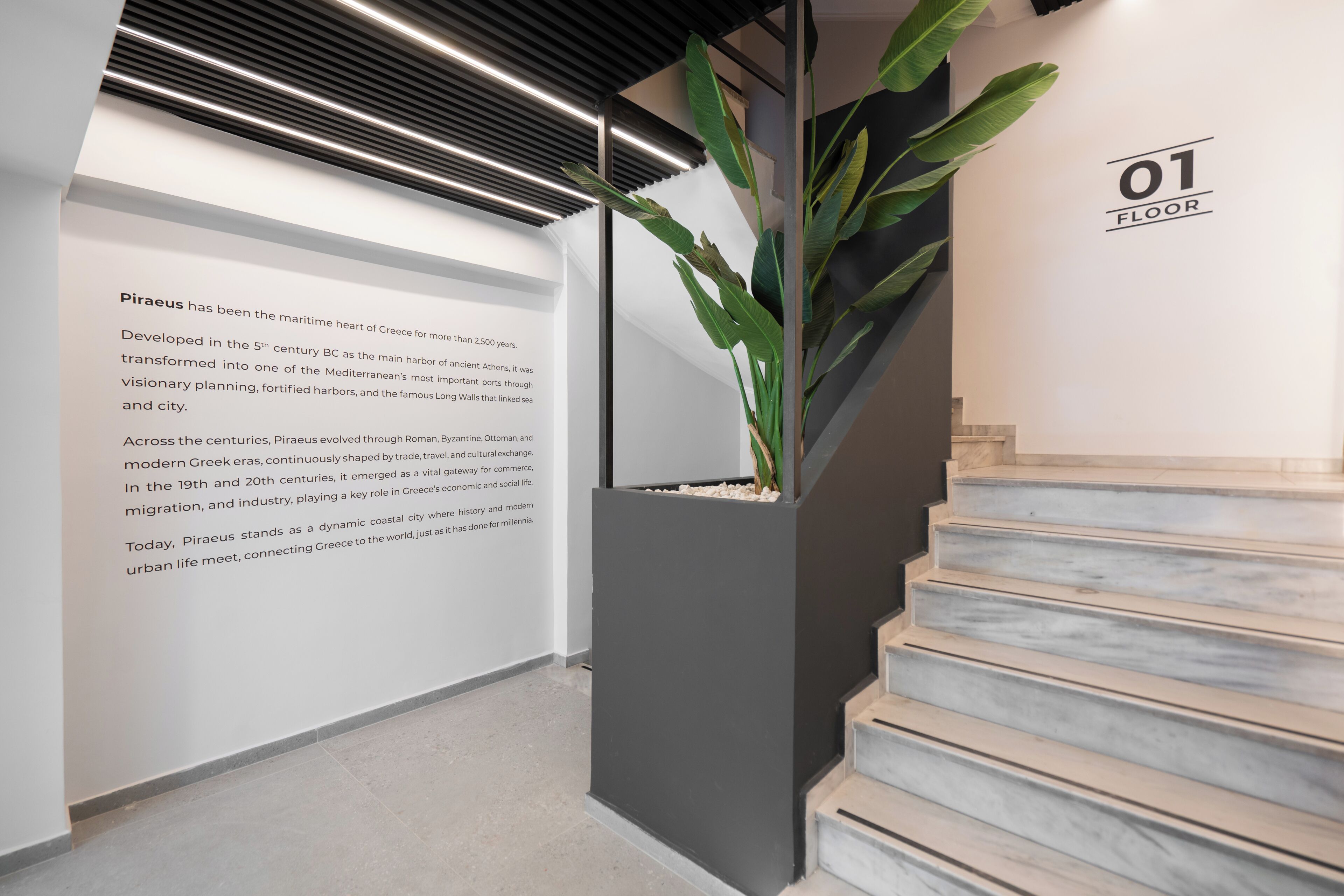 Een modern interieur met een trap, een potplant en informatie op de muur.