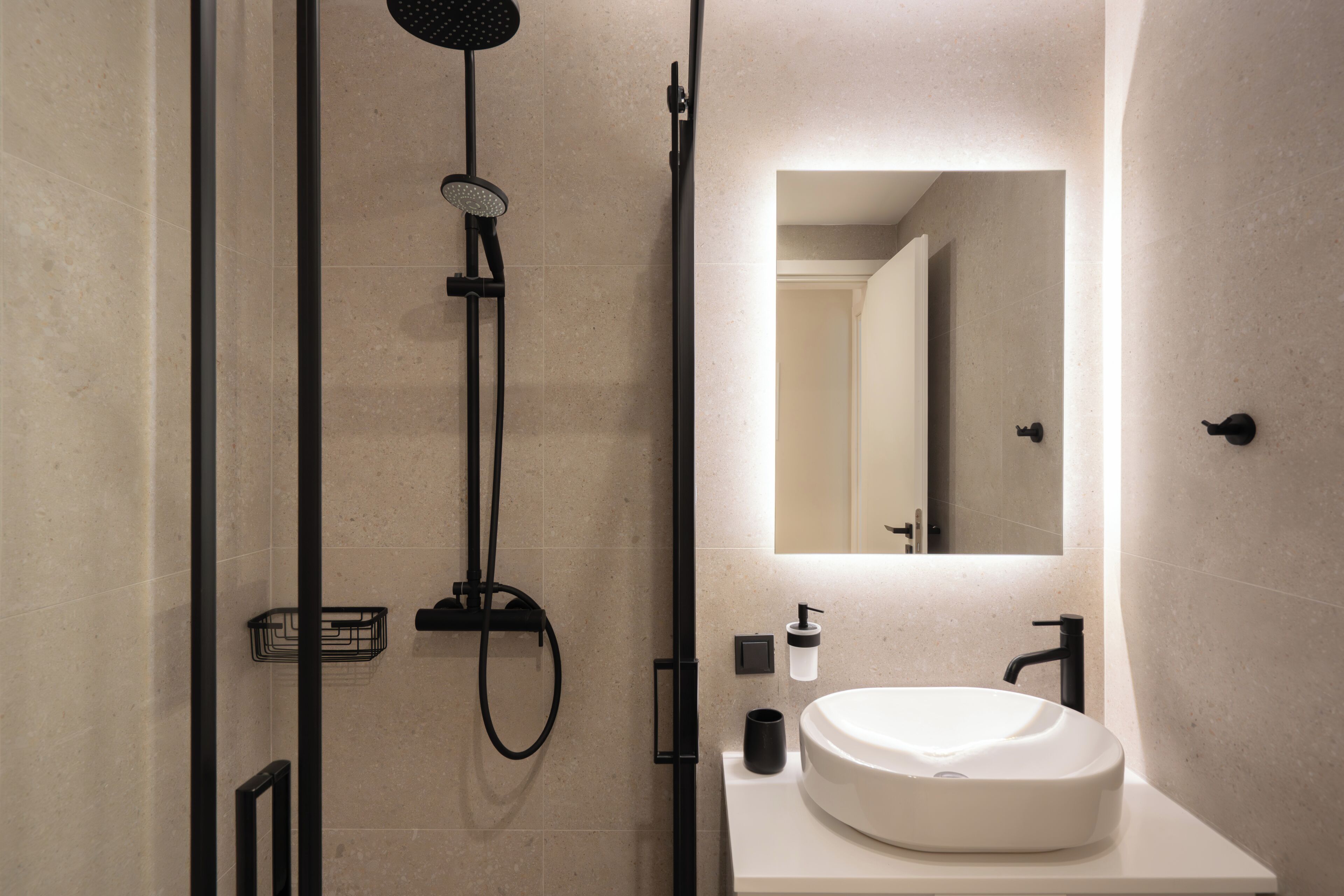 Un bagno moderno con doccia, lavabo e specchio.