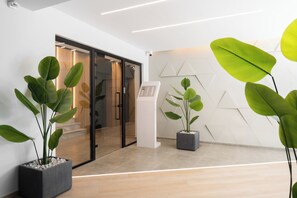 A modern lobby with a reception desk, potted plants, and a geometric wall design. - The Edge Piraeus Luxury Residences (Piraeus)