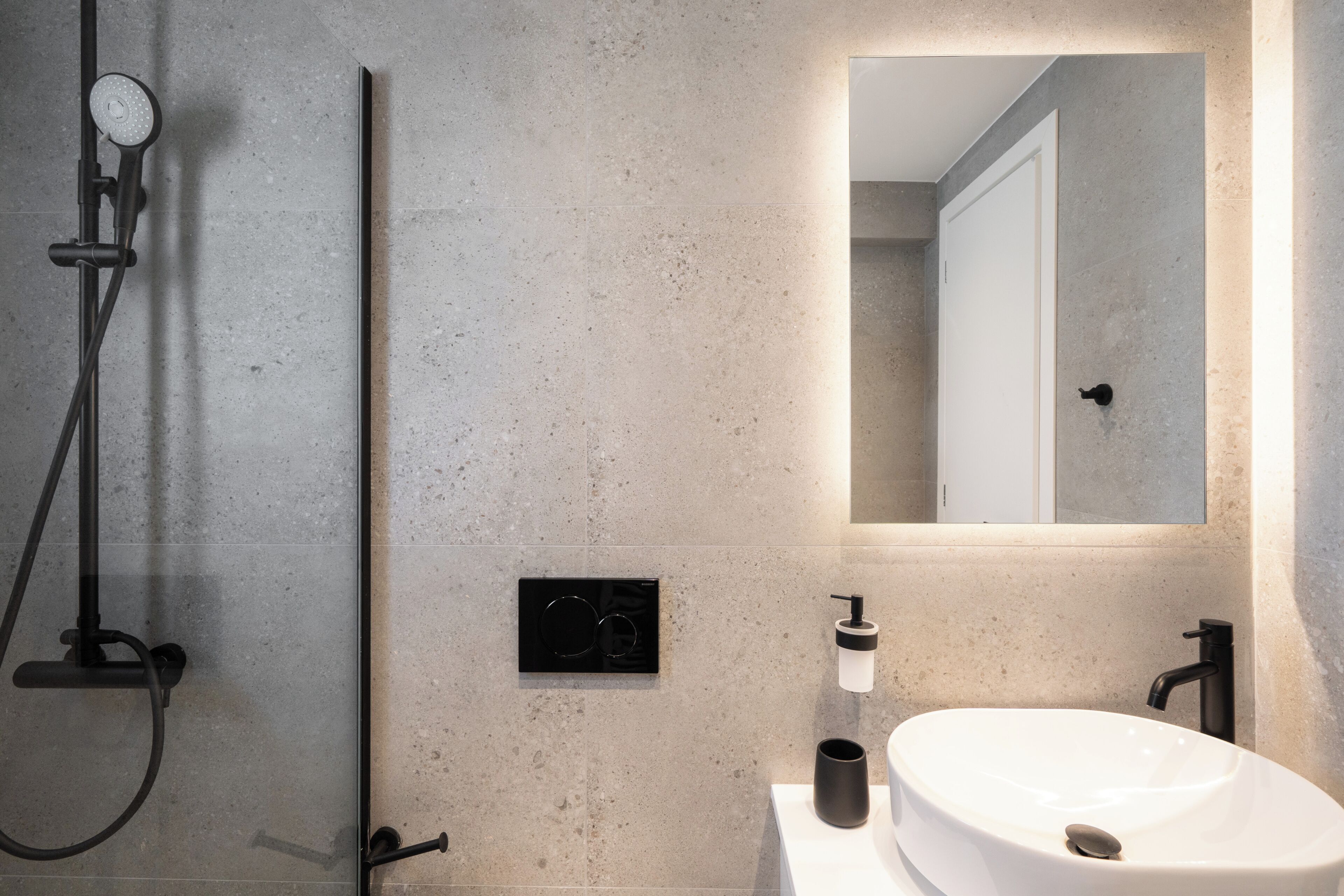 A modern bathroom with a shower, a sink, and a mirror.