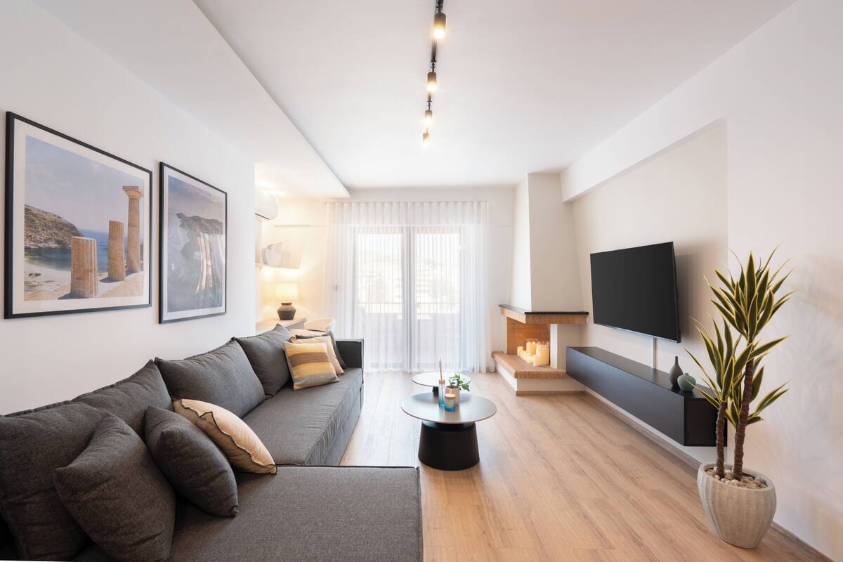 A modern living room with a sofa, a coffee table, a TV, and a fireplace.