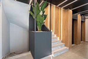 A modern staircase with a planter, wooden paneling, and a ceiling with linear lighting. - The Edge Piraeus Luxury Residences (Piraeus)