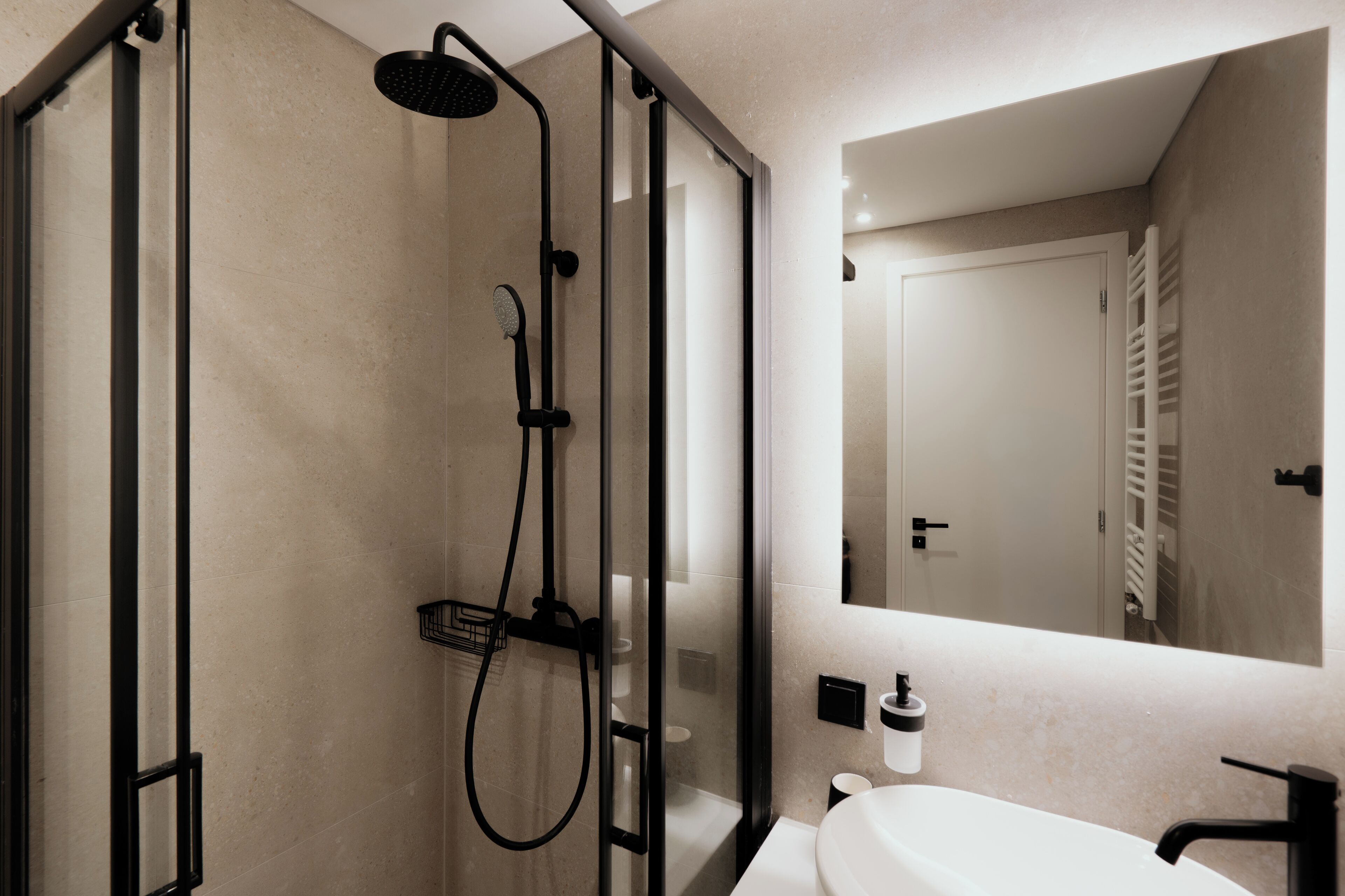 Une salle de bain moderne avec une douche à parois de verre, un lavabo blanc et un miroir au-dessus du lavabo.