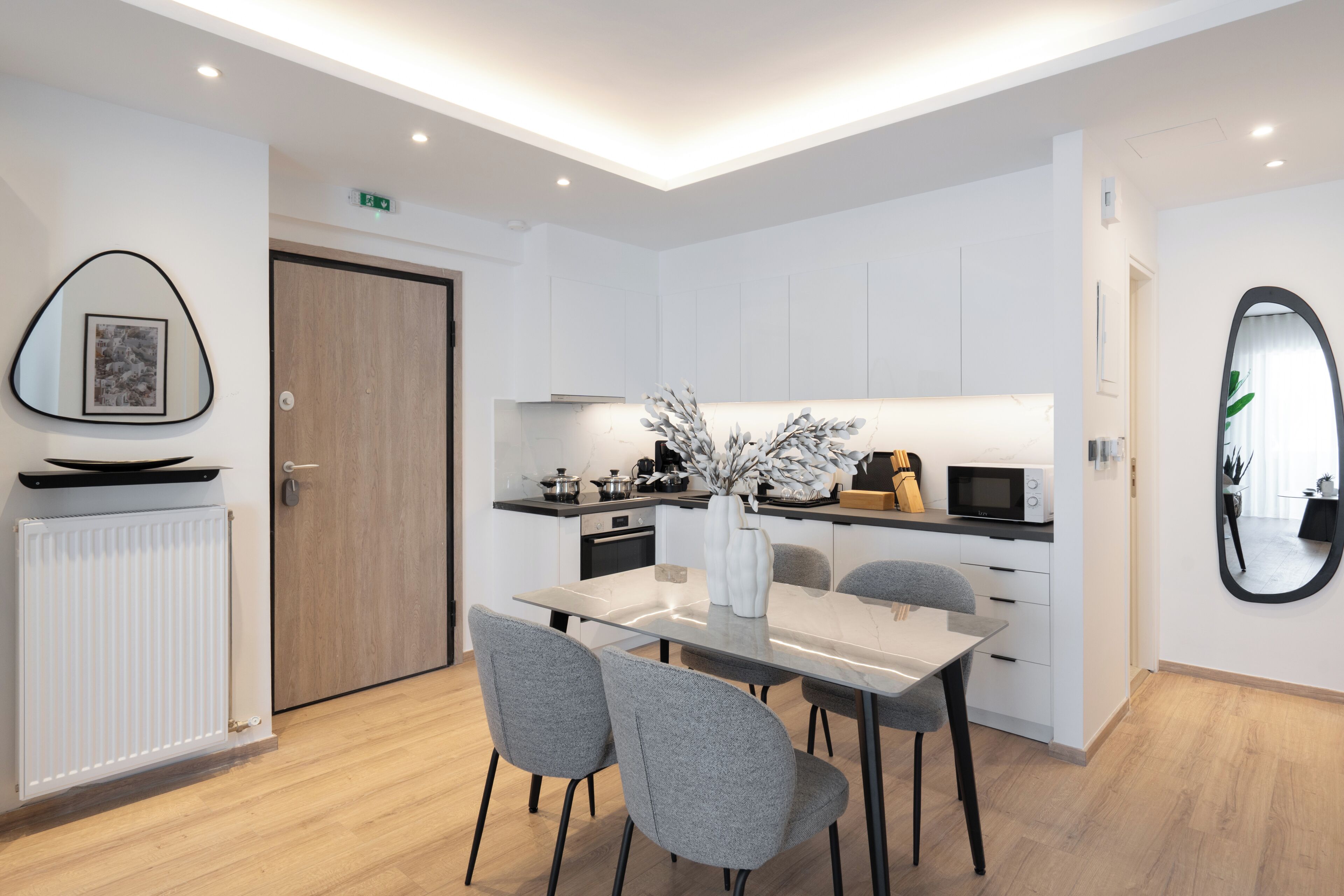 A modern kitchen with white cabinetry, a dining table with chairs, and a built-in microwave.
