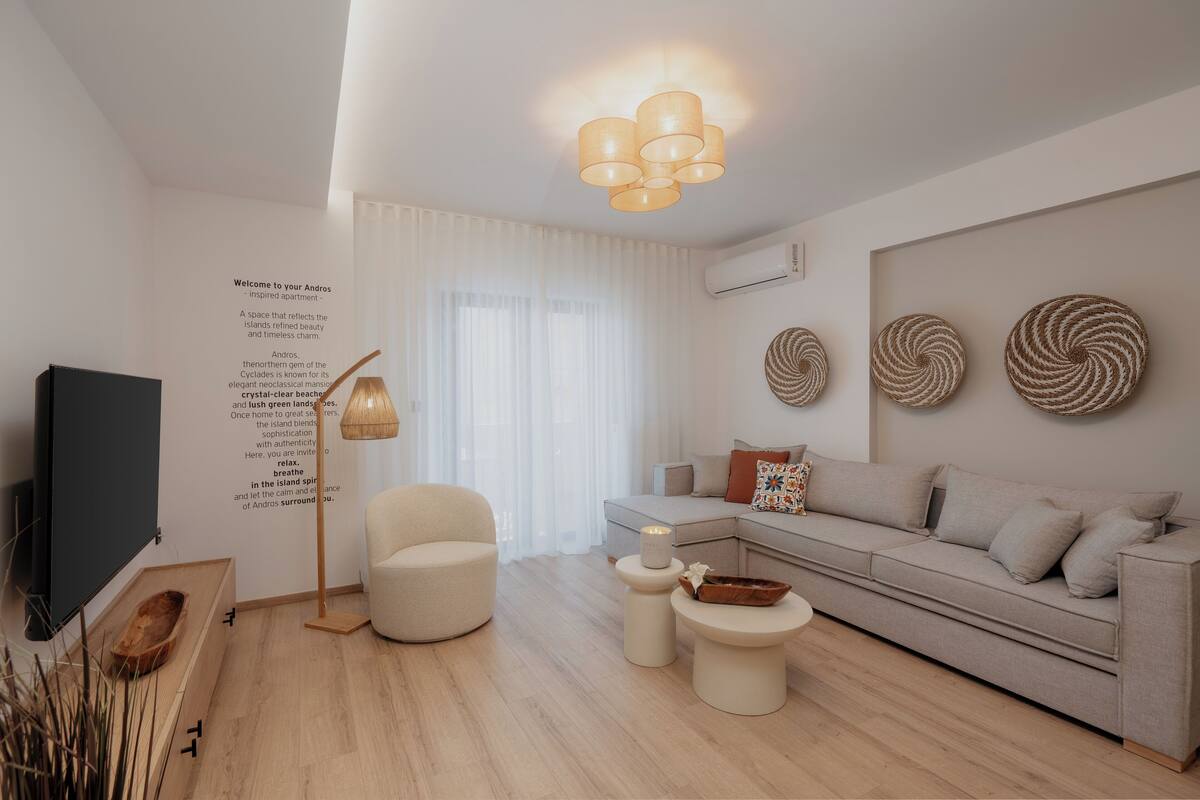 A modern living room with a sofa, armchair, TV, and decorative wall art.