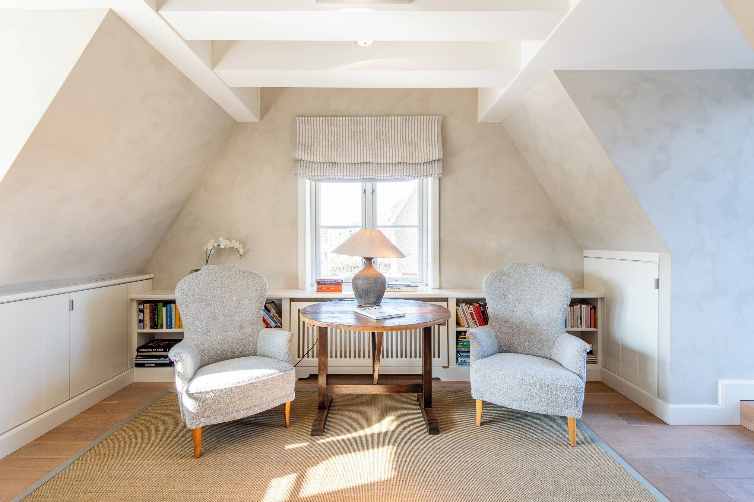 Un coin lecture confortable avec deux fauteuils, une table ronde et une lampe.