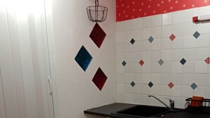 Una cocina compacta con un lavamanos, una mesa de comedor con sillas y un patrón decorativo en los azulejos de la pared.