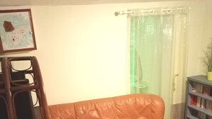 Sala de estar con un sofá de cuero marrón, una silla de madera, una estantería y un cuadro en la pared.