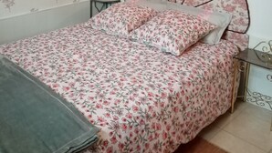 Un dormitorio con una cama, una mesita de noche y un papel tapiz floral en la pared.