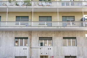 Ein mehrstöckiges Gebäude mit Balkonen, Fensterläden und einer Betonfassade.