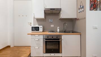 A compact kitchen with a microwave, stove, oven, and sink.