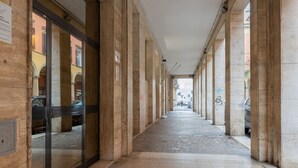 A corridor with stone columns, a tiled floor, and a glass door on the left. - Nido di Galliera by Wonderful Italy (Bologna)
