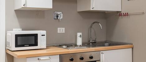 A compact kitchen with a microwave, oven, sink, and cabinets.