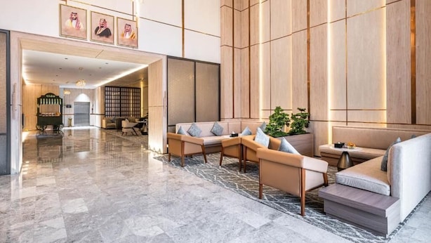 Eine geräumige Lobby mit Marmorboden, einer Sitzecke mit Sofas und Sesseln sowie einer großen Wand aus Holzpaneelen.