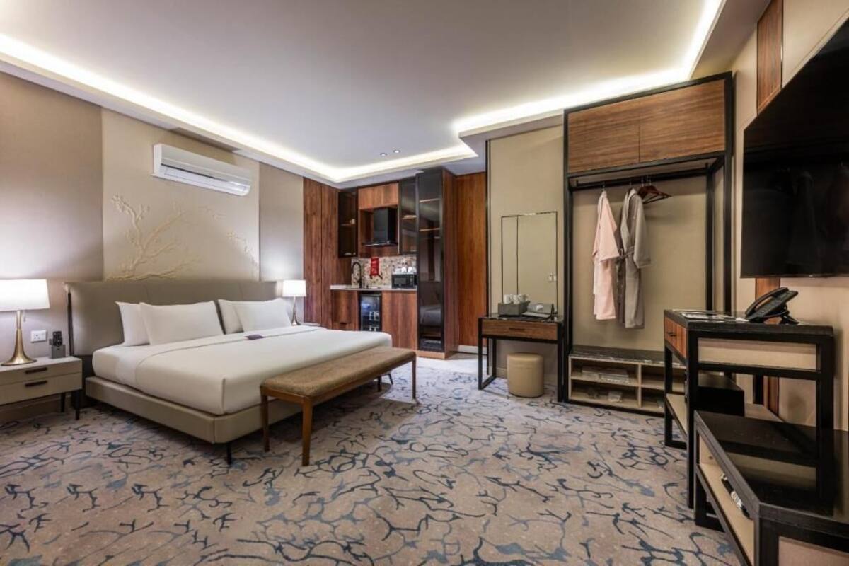 A hotel room with a bed, bedside table, lamp, wardrobe, and a television.