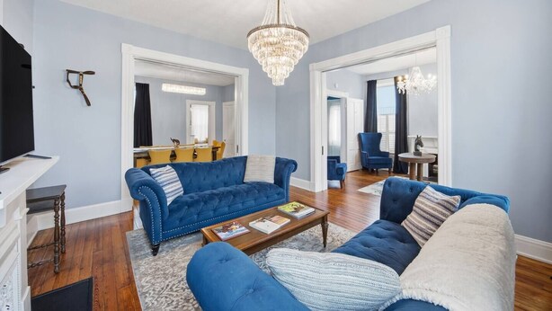 Ein Wohnzimmer mit blauem Sofa, einem Holztisch und einer Kristallleuchter.