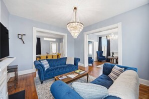 A living room with a blue sofa set, a wooden coffee table, and a chandelier. - The Parsonage of Paris (Paris)